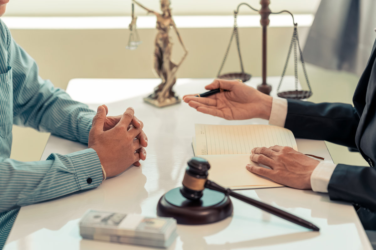 A notary or notary works with contract documents and knocks with a gavel in a legal courtroom. A lawyer advises clients during legal discussions.