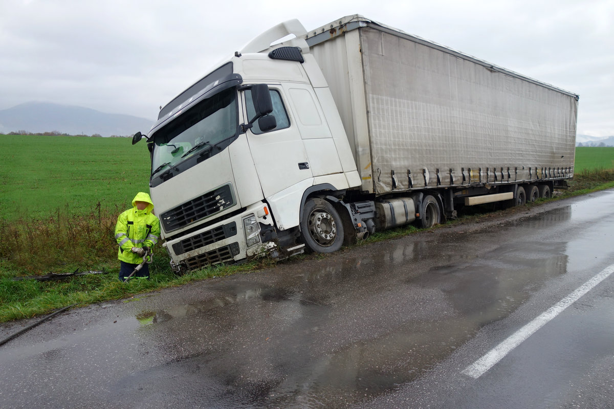 Real event. Car accident. The truck lies in a ditch after the road accident over raining day in autumn time. Rescuers help with car accident.
